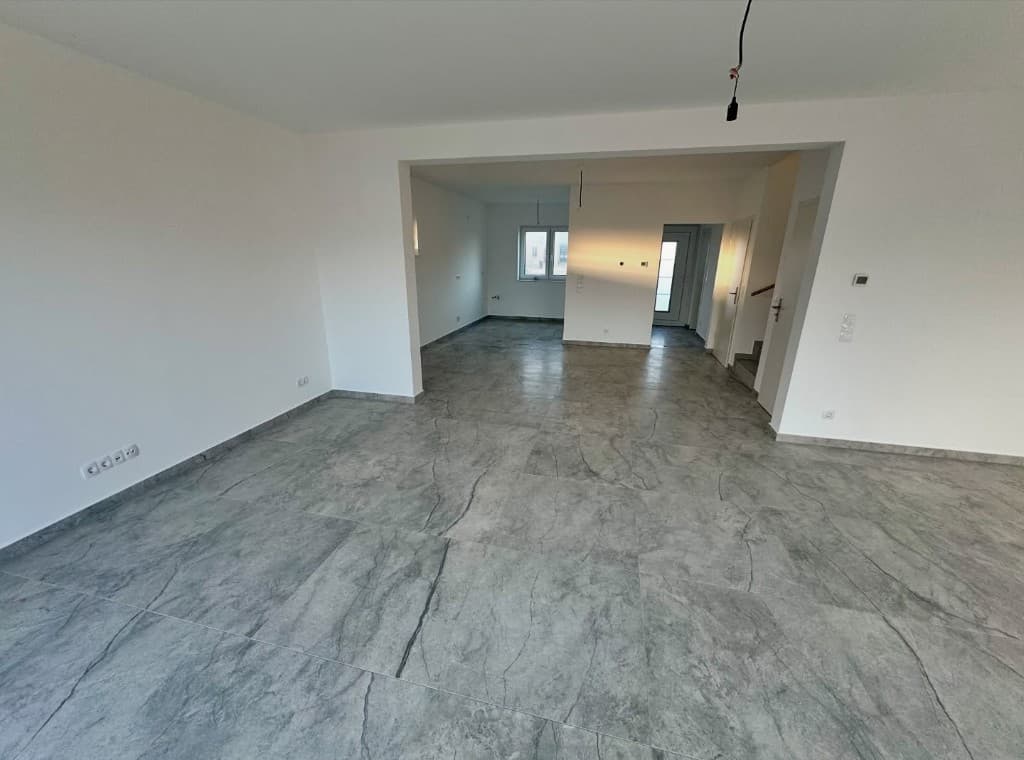 Large empty room with grey marble-vein floor tiles and white walls