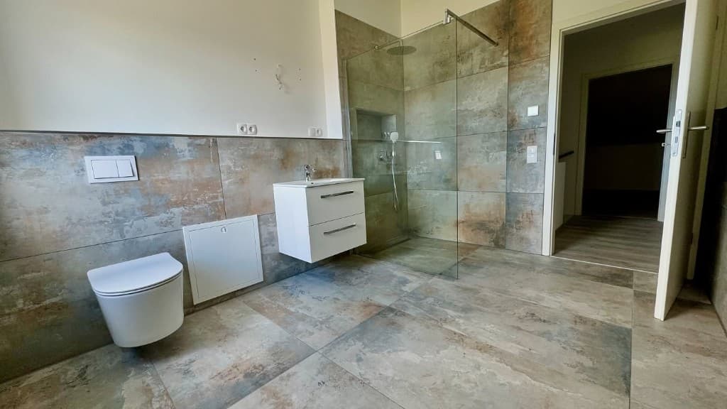 Modern bathroom with stone-look tiles, wall-hung toilet, vanity and walk-in shower